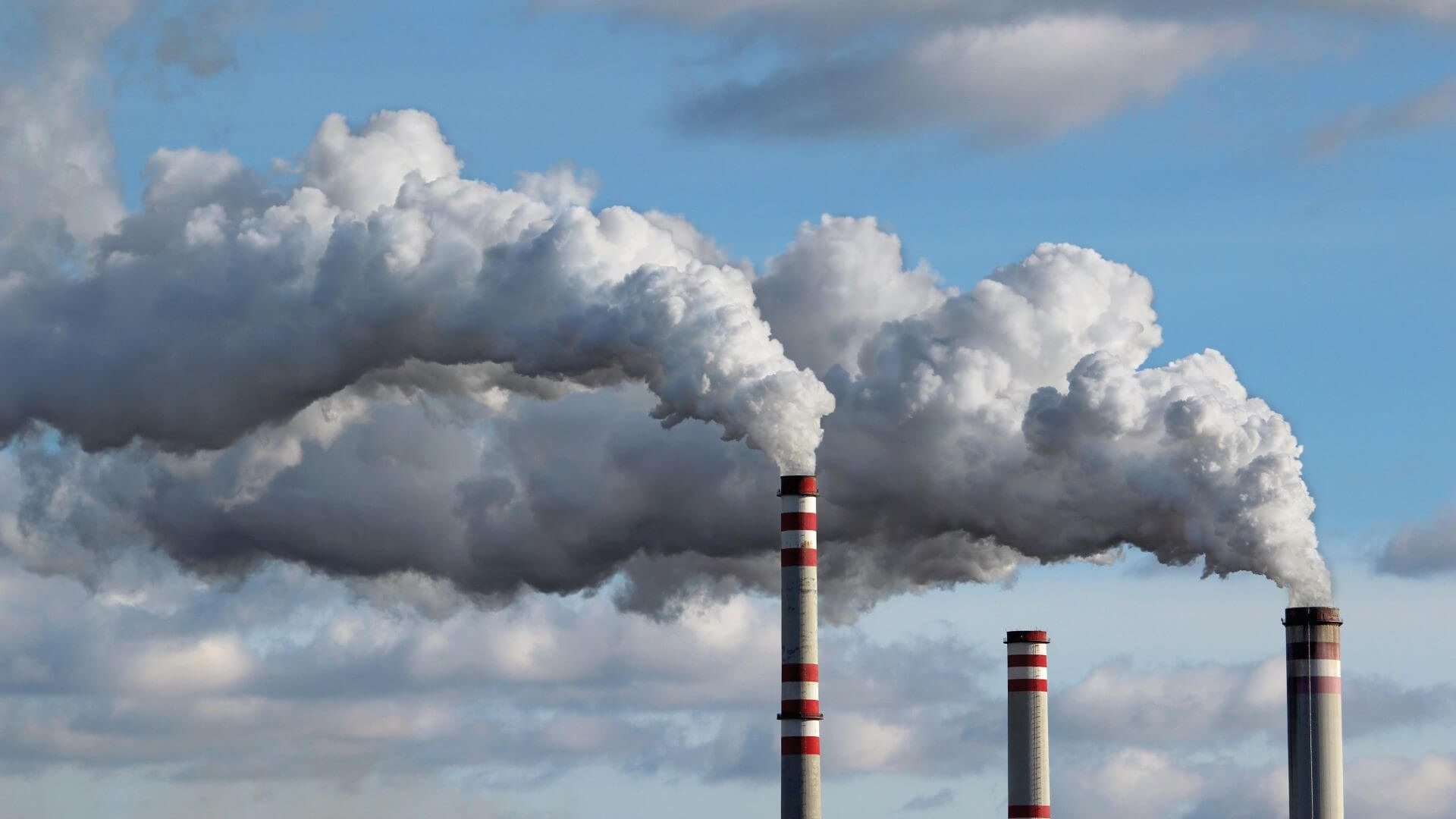 Three industrial chimneys against blue sky