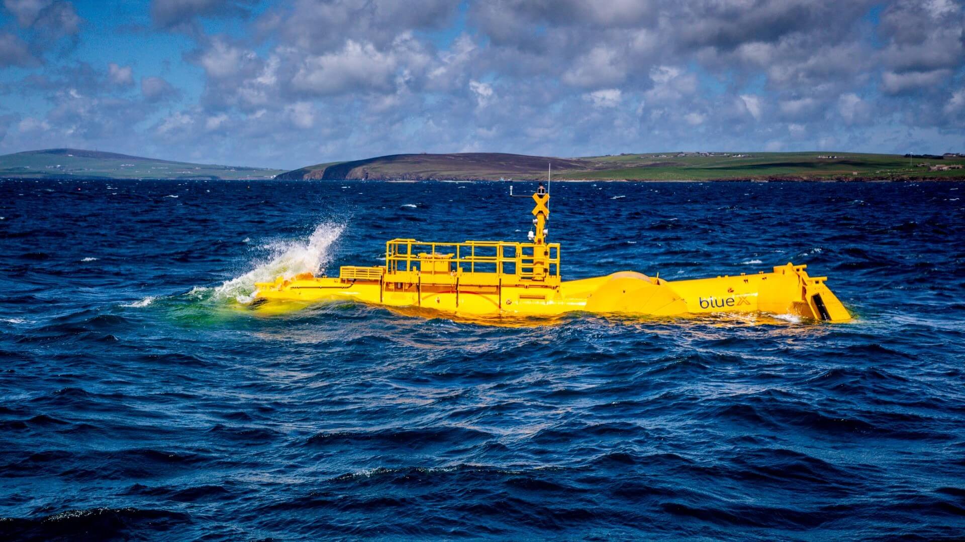 Bright yellow prototype wave energy converter on surface of sea