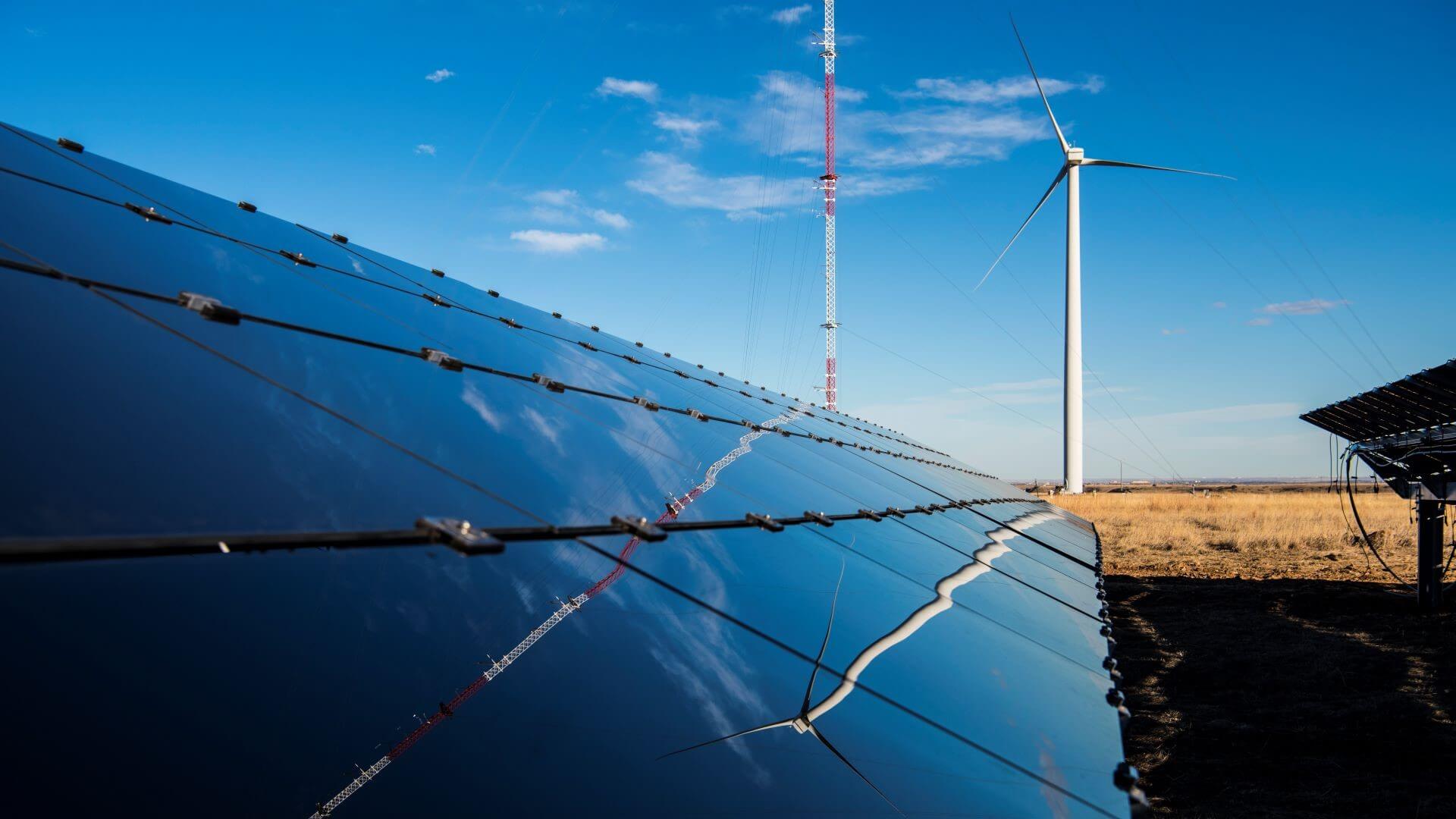 Close up of bank of solar panels extending into distance set against blue sky 