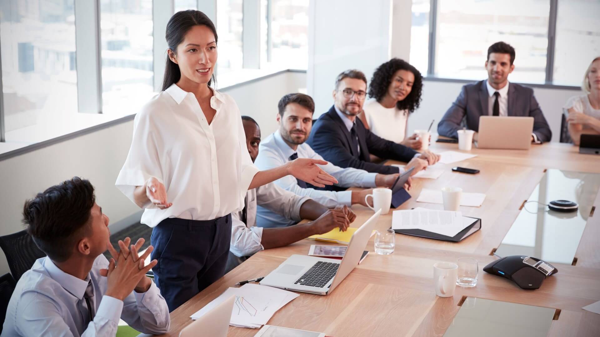 People sat around a table with woman leading a business meeting 