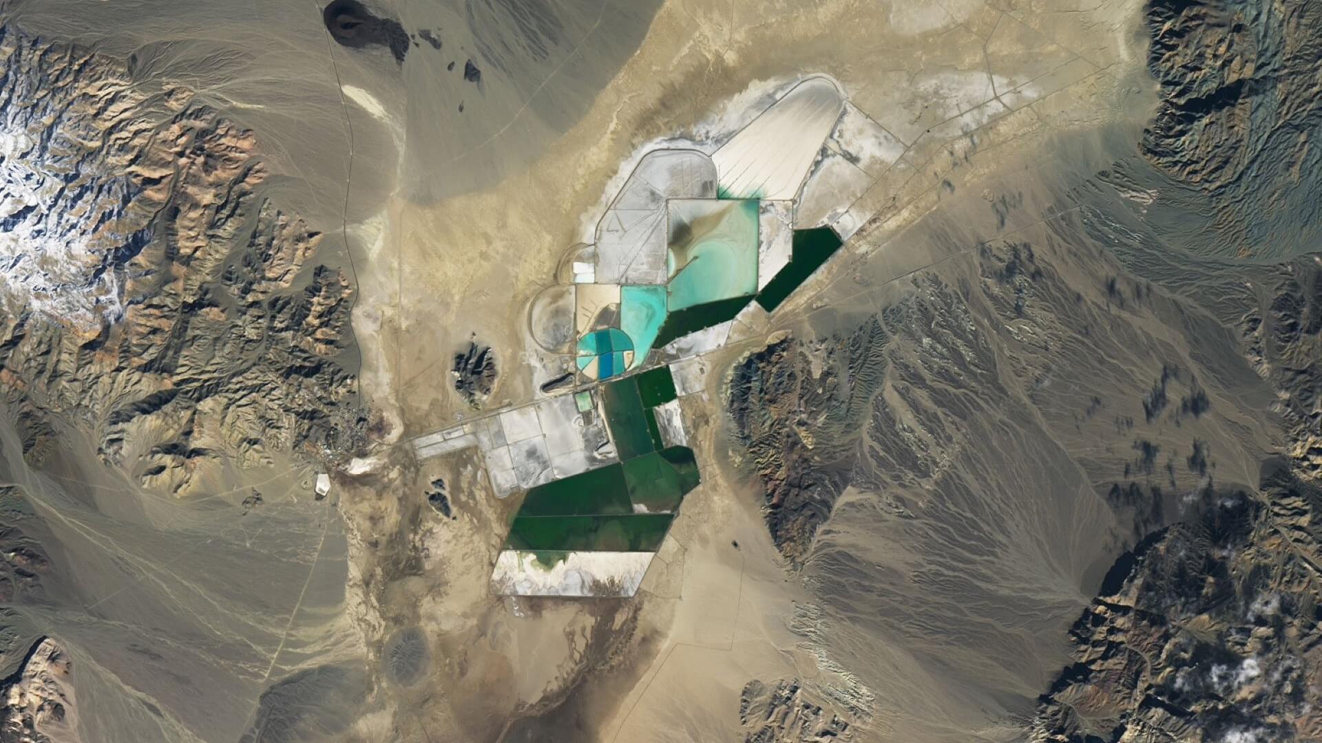 Satellite view of turquoise salt ponds set against brown earth