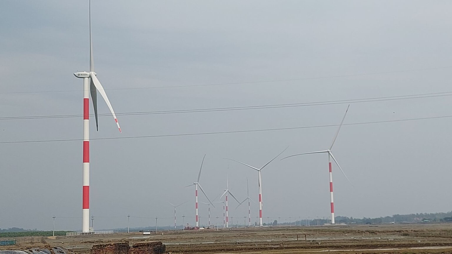 Distant view of wind turbines set against grey sky