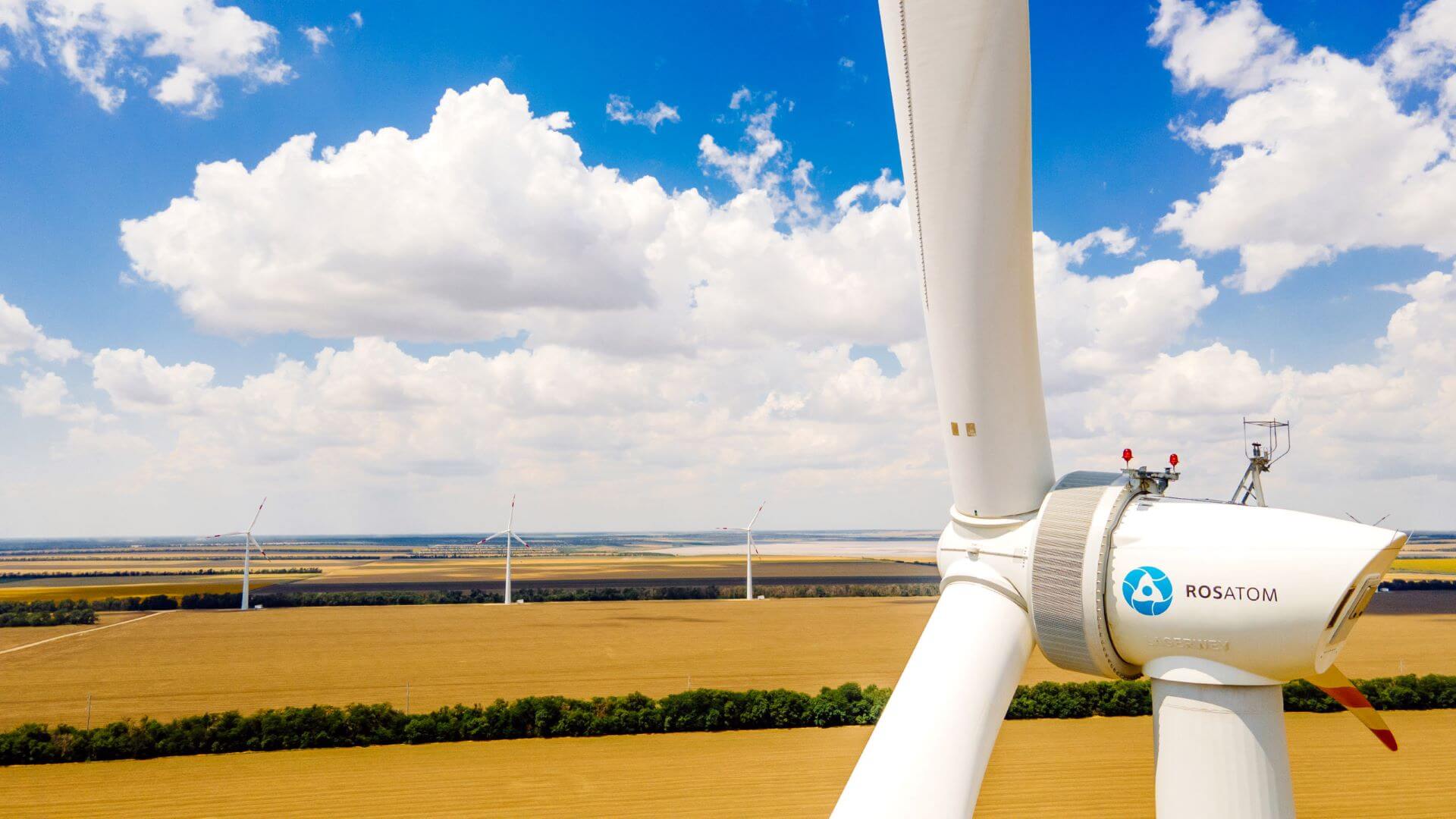 Close up of wind turbine in field against blue sky with clouds