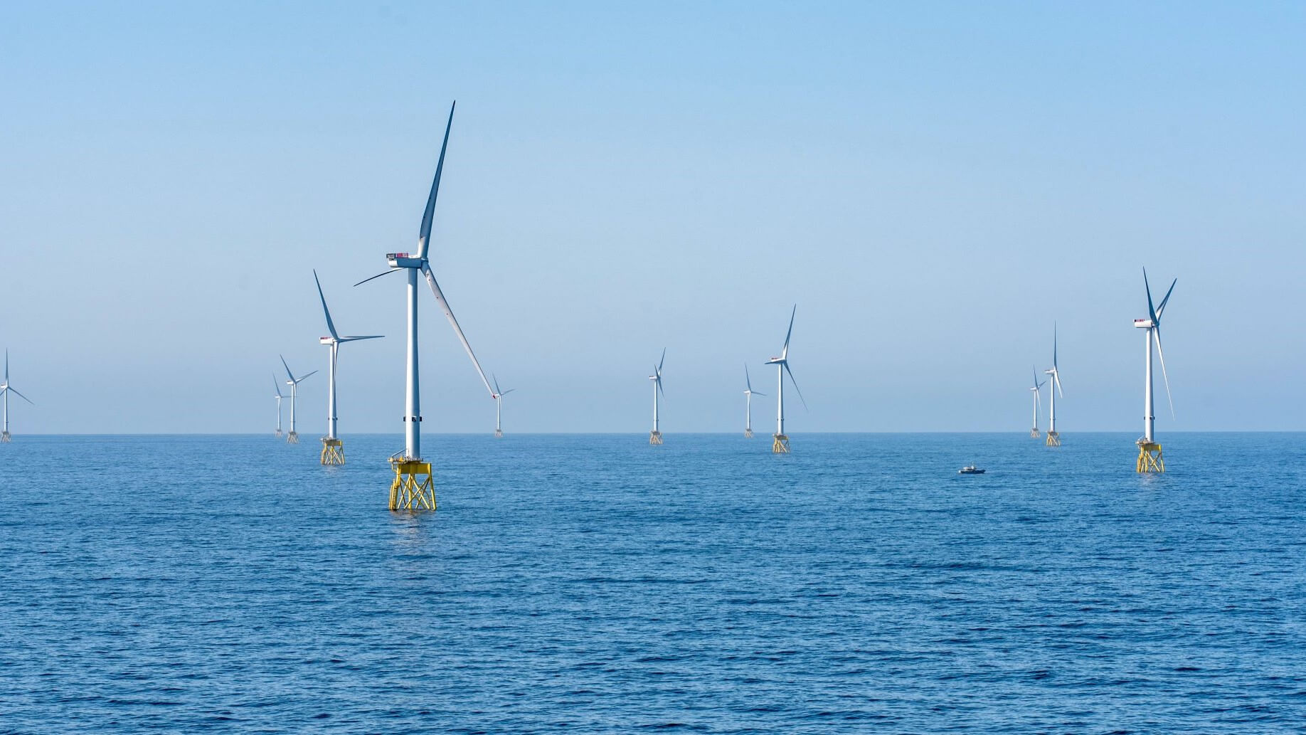 Offshore wind turbines in calm sea with blue skies behind