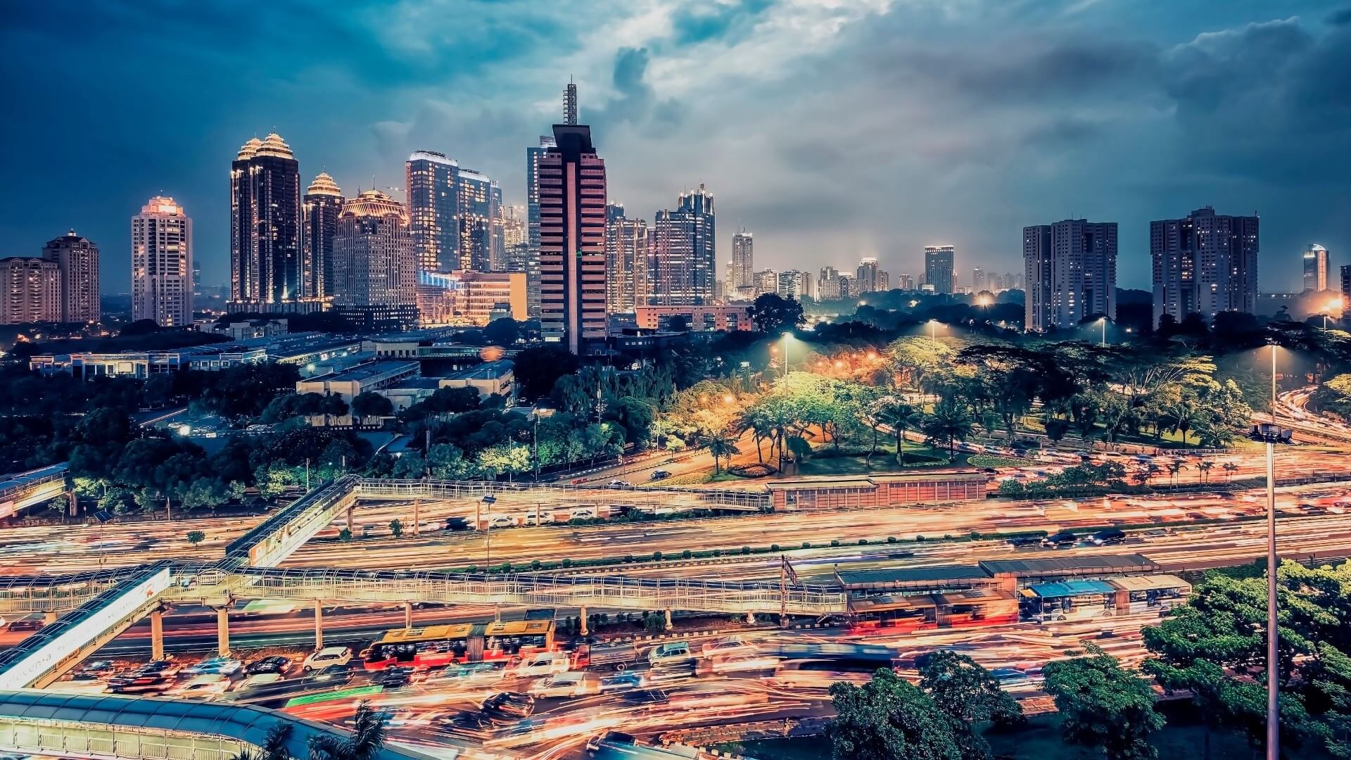 Lit up skyline of Jakarta, Indonesia, with busy road in foreground
