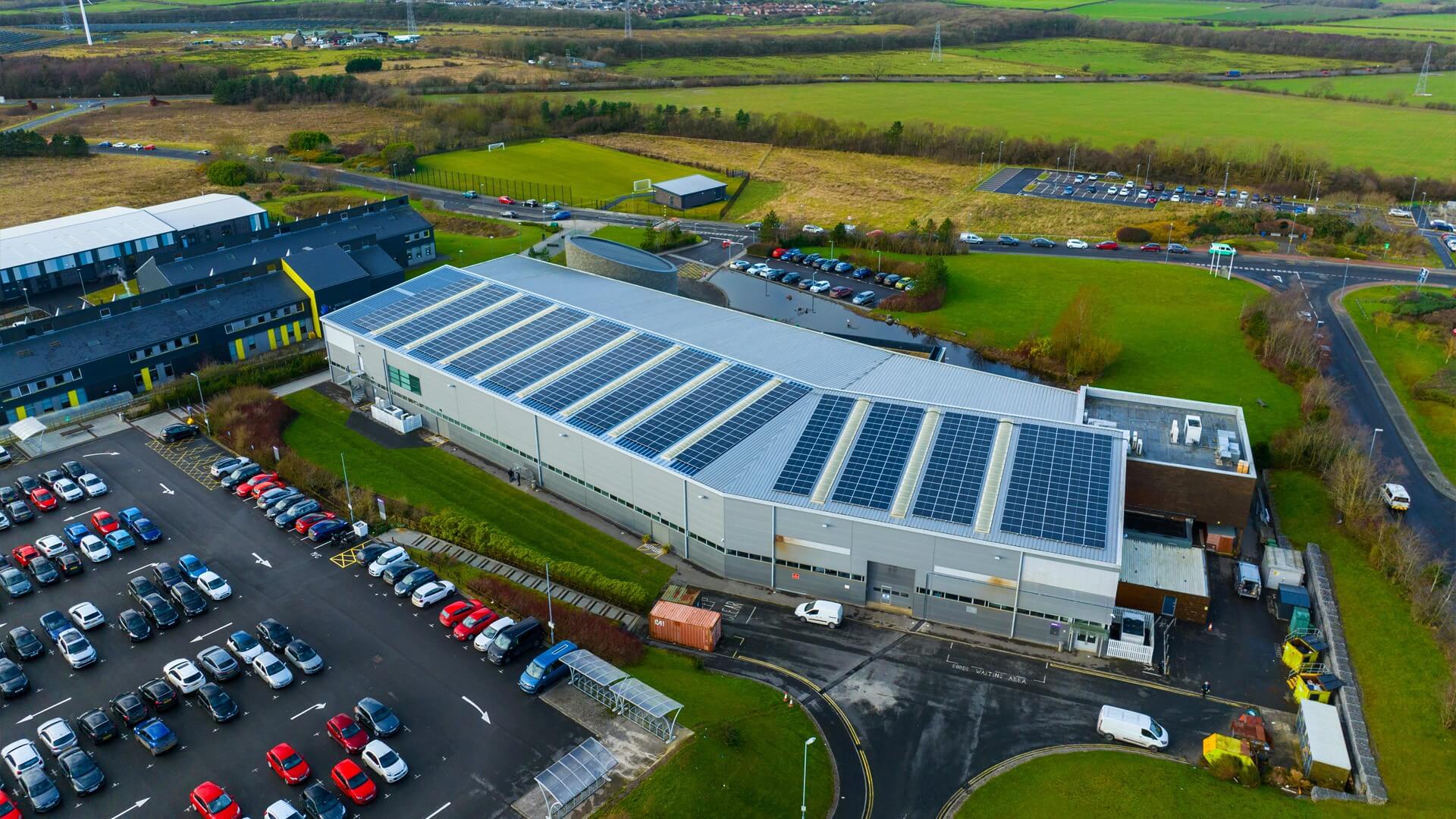 Aerial view over large conference centre building with roof covered in solar panels