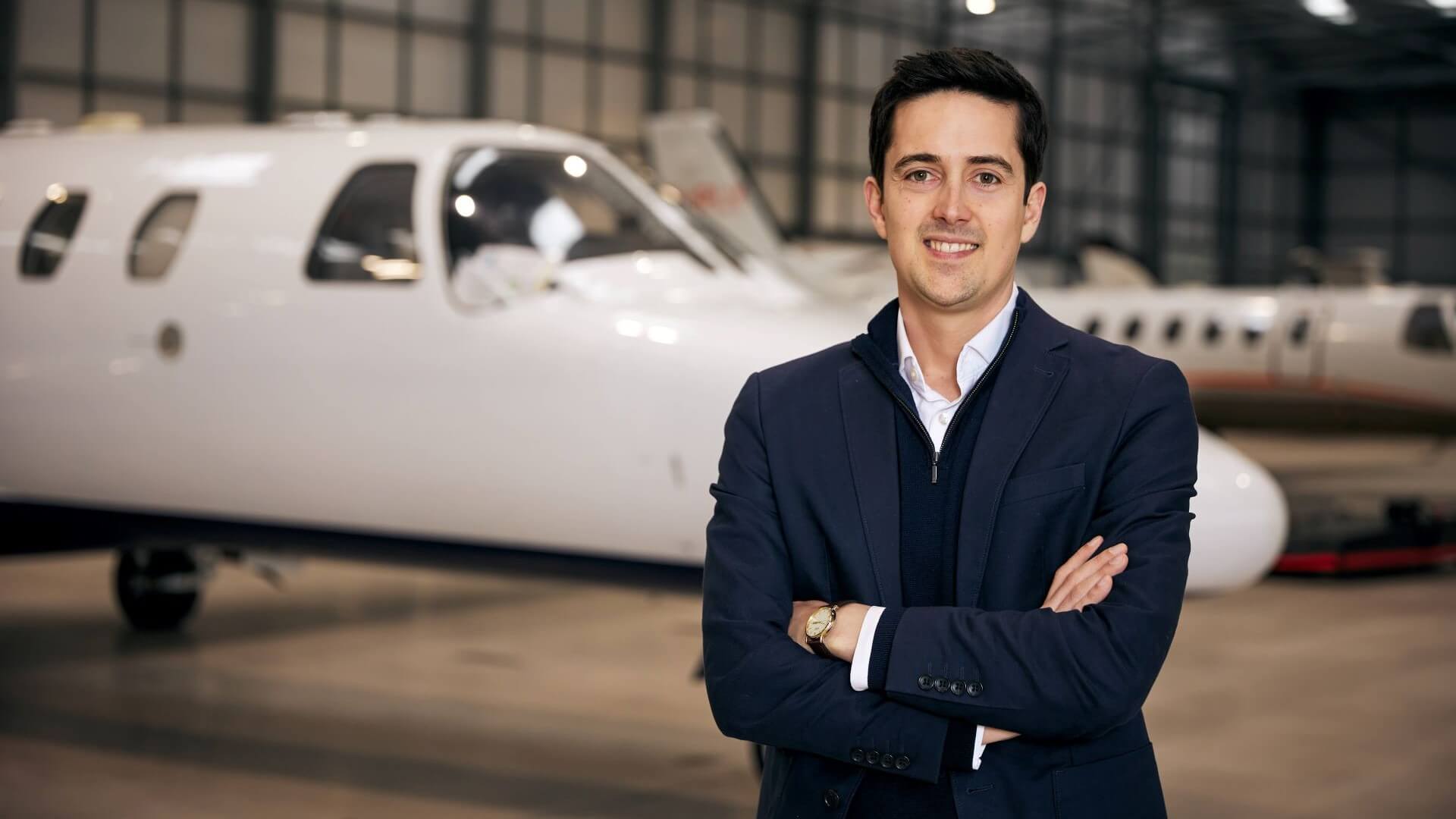 Head and shoulders photo of Andrew Symes, CEO of OXCCU with executive jet in background