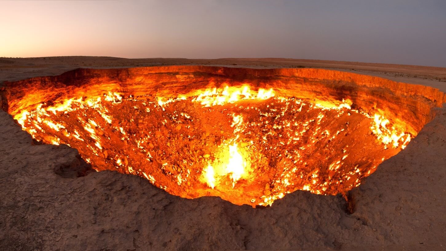 Aerial view over raging orange flames in crater 