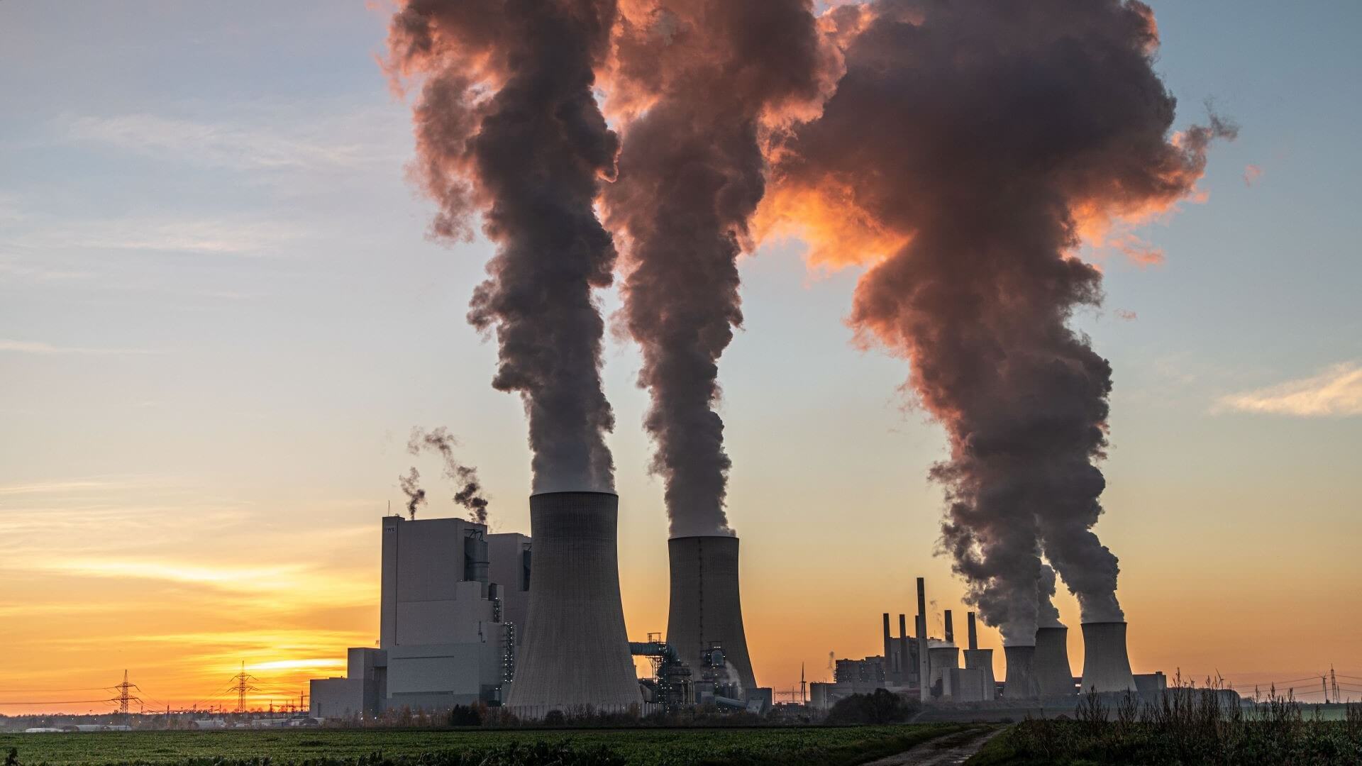 Coal plant silhouetted against sunset sky, with billowing vapours heading skywards