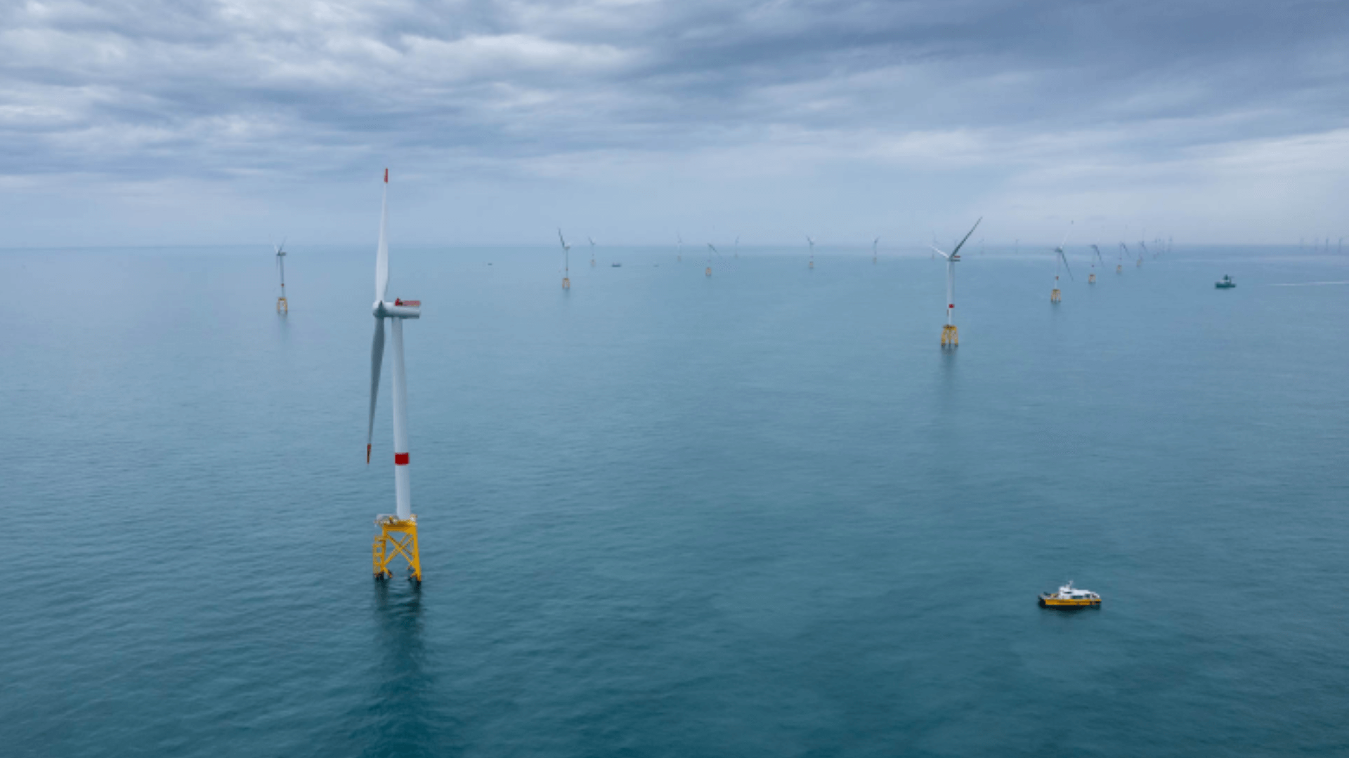 Aerial view over see with a number of floating offshore wind turbines dotted about the calm waters