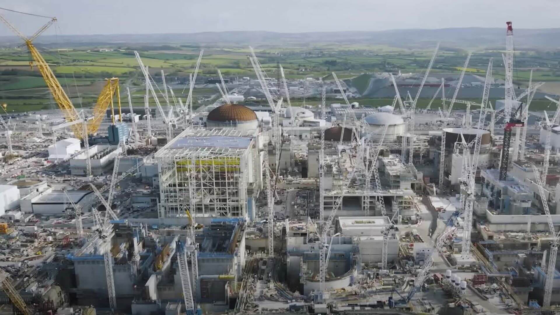 Aerial view over construction site with many part-built buildings and domes and lots of cranes