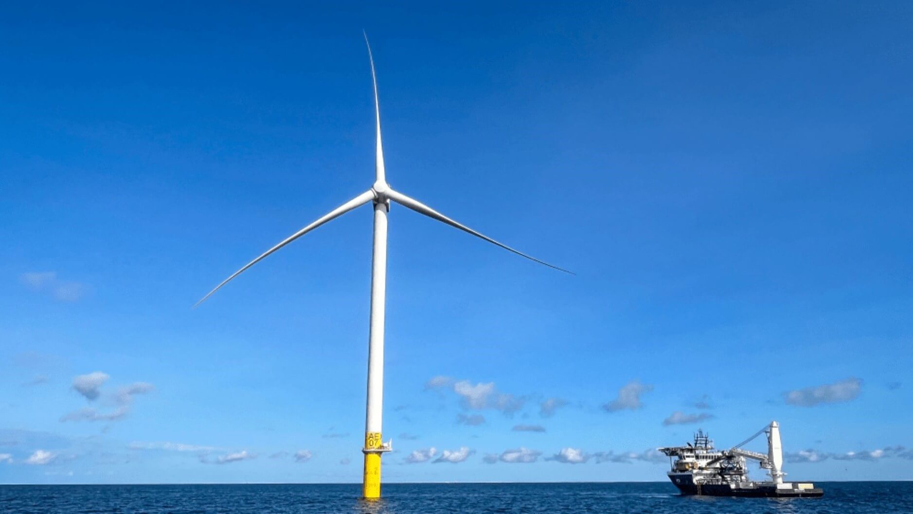 Offshore wind turbine and boat on calm sea