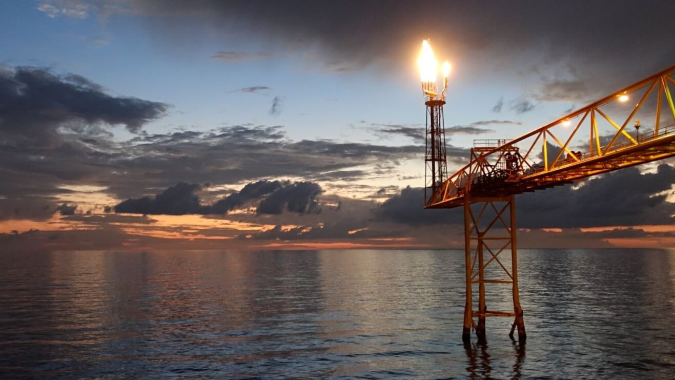 Flare burning from offshore platform at dusk