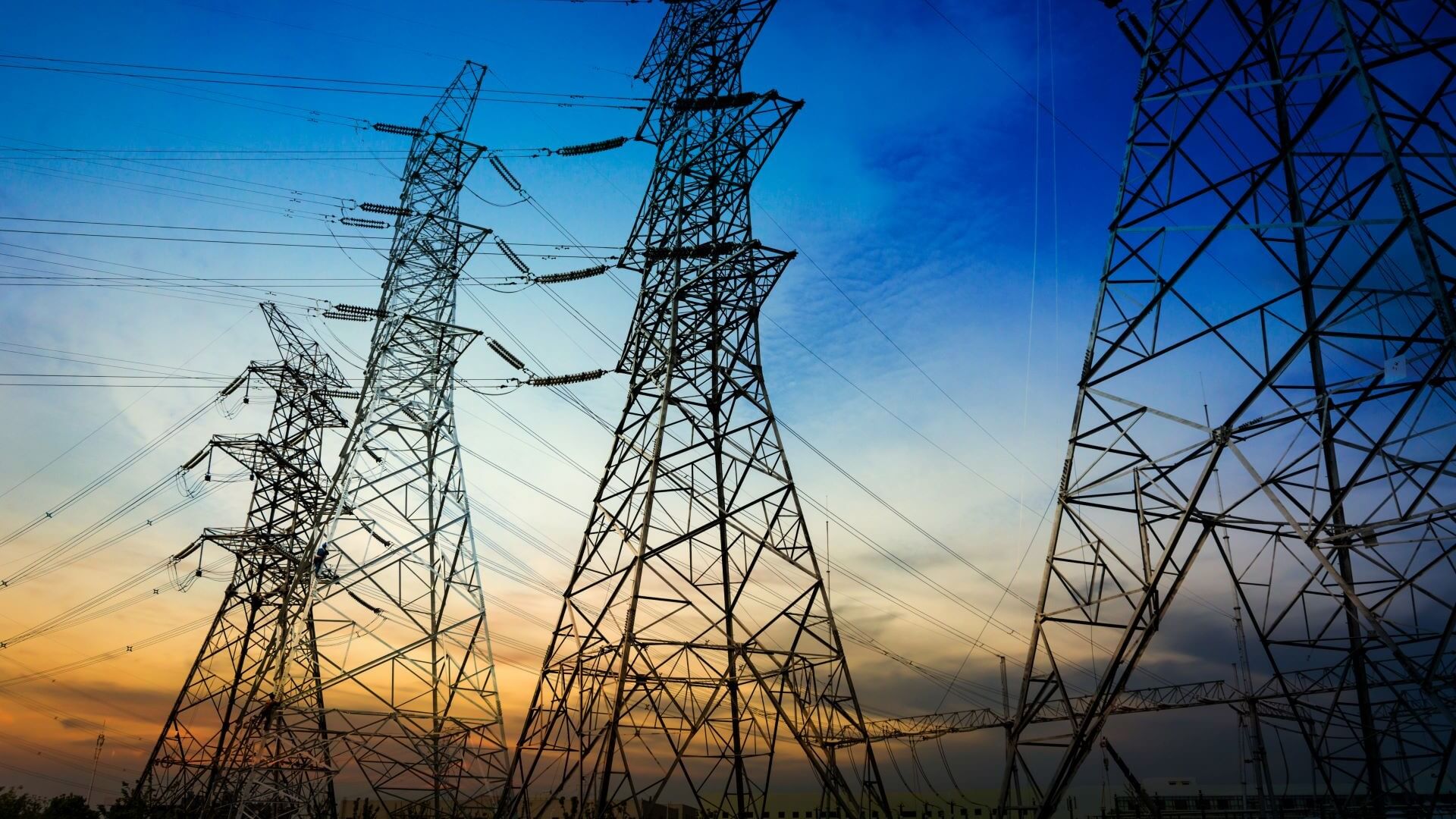 Electricity pylons silhouetted against sunset sky