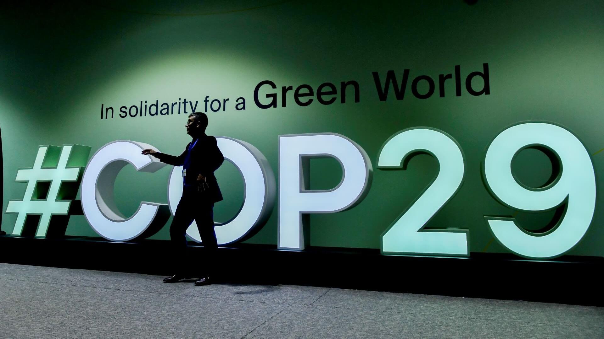 Silhouette of person stood in front of COP29 sign at conference