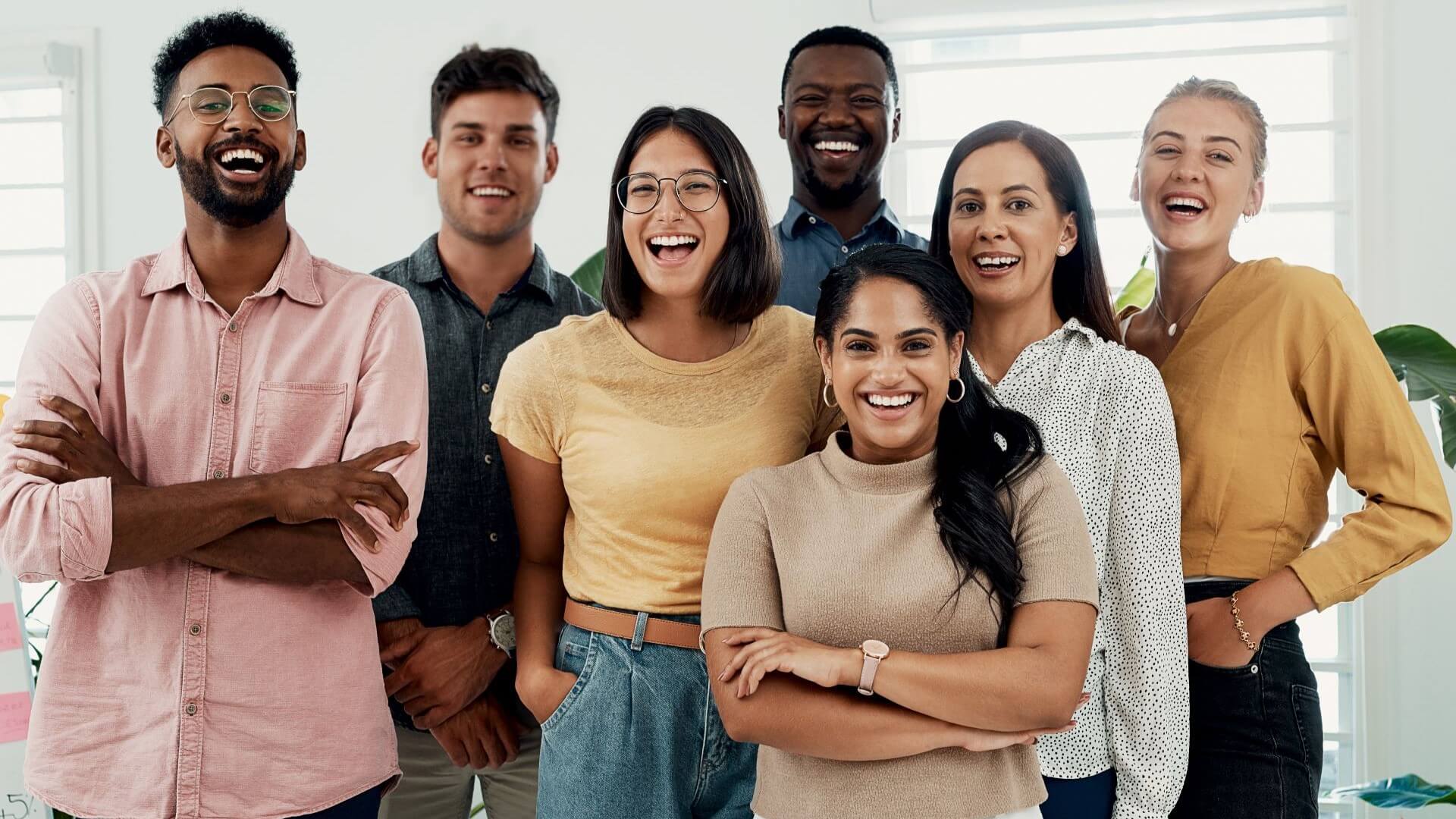 Group of young professionals standing together and smiling at the camera taking photograph