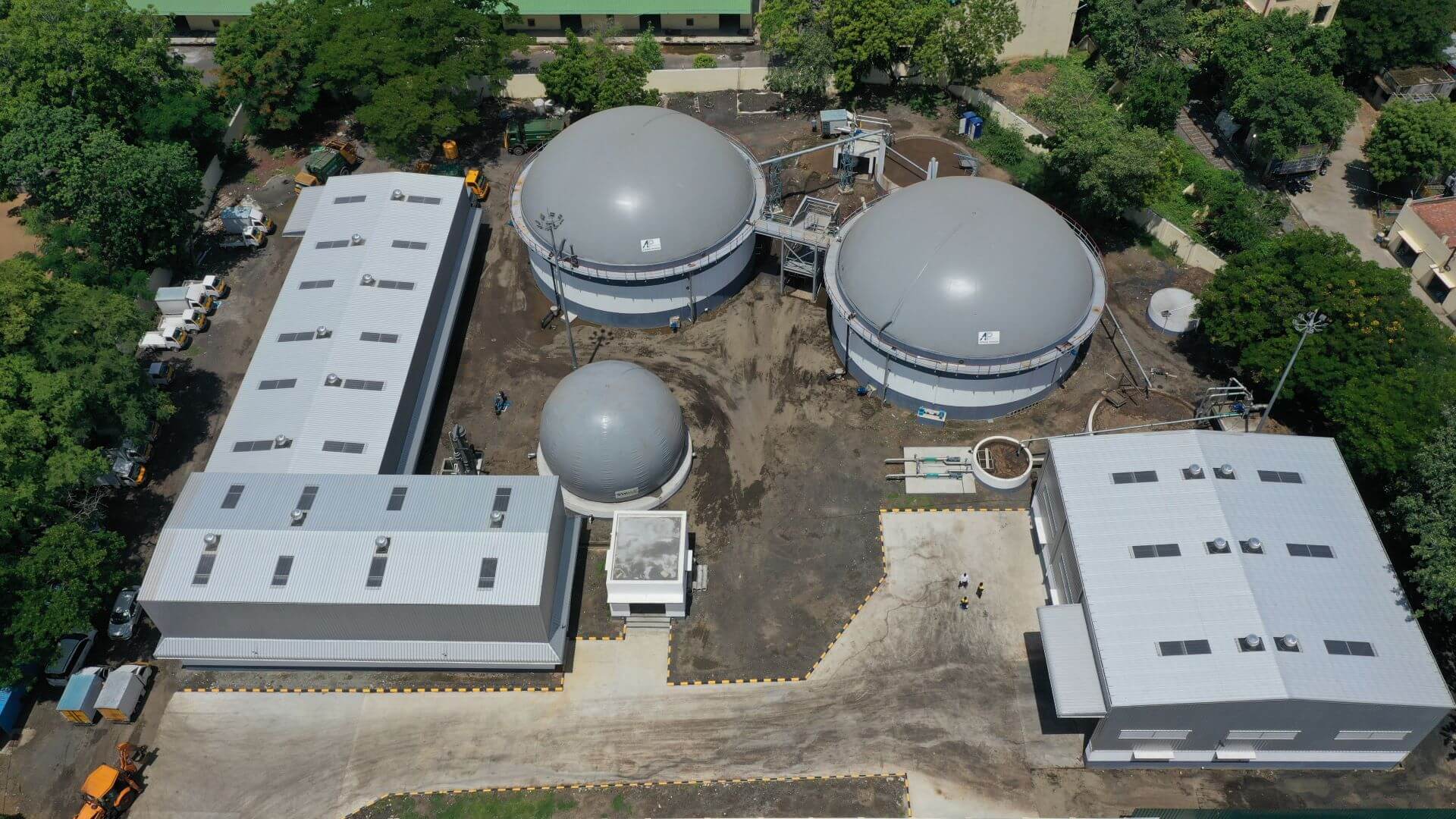 Aerial view of biogas plant round storage tanks and rectangular and L-shaped buildings