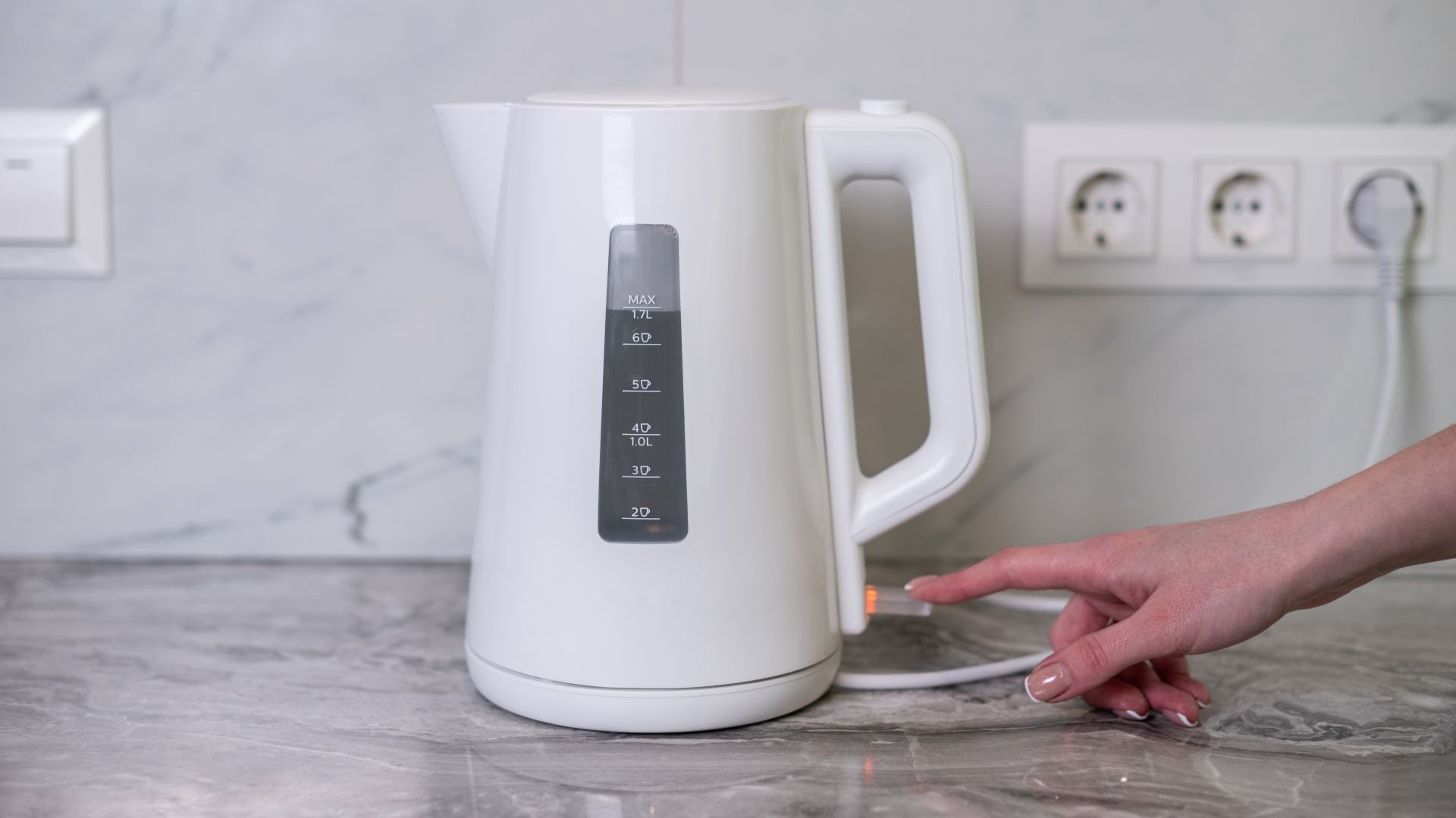 Boiling metal kettle with handle arching over top and a black knob, with steam billowing out of spout