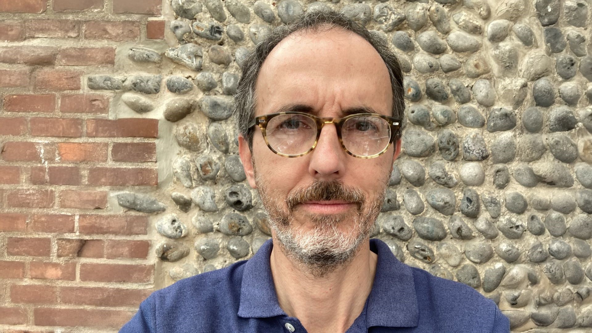 Head and shoulders photo of Chris Hilson standing in front of brick and pebble wall