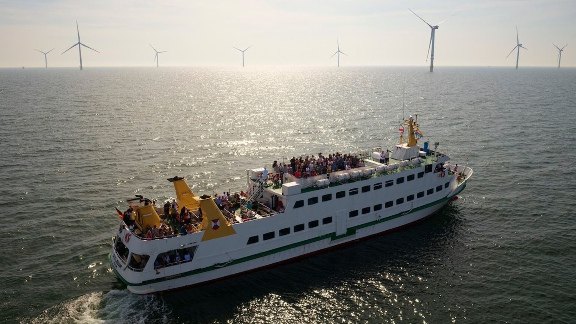 Passenger ferry in foreground, with offshore wind farm on distant horizon